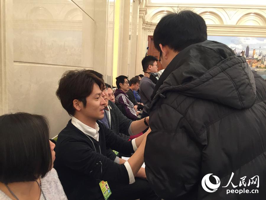 某代表团开放日上，一位日本记者借相机给我网记者，图中的他正在讲述相机用法。