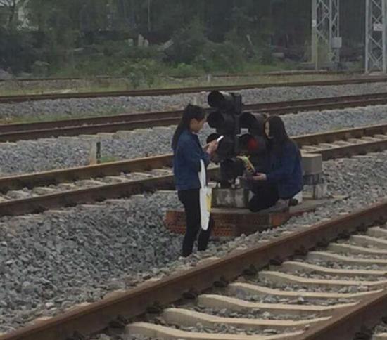 两名女士在铁轨之间玩耍拍照，而火车即将开来。 长沙晚报通讯员 朱红梅 李兴阳 摄