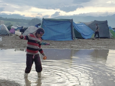 在难民营中，一个女孩正在趟水而过。