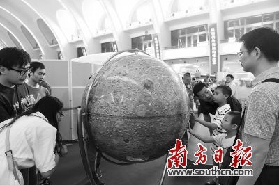 5日，在国家“十二五”科技创新成就展上，参观者观看展出的“嫦娥一号月球仪”。新华社发