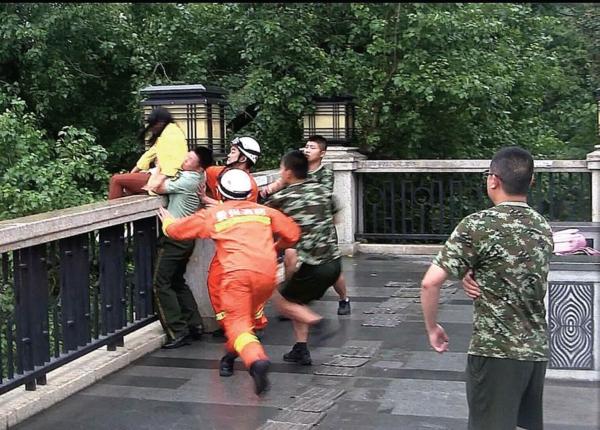 女子坐桥栏杆欲跳河 消防员拦腰飞抱将其救下