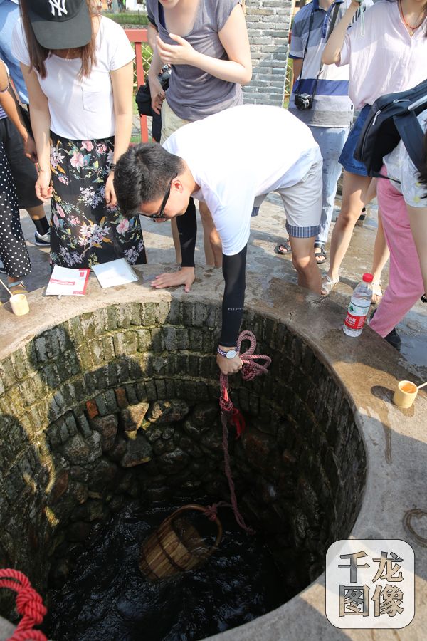 图为参观人员在红井旁亲身体验打井水