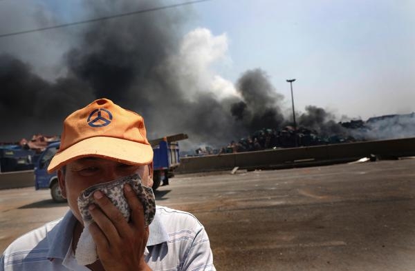 8月13日,天津,滨海新区危险品仓库爆炸现场附近,一名行人捂住了嘴巴