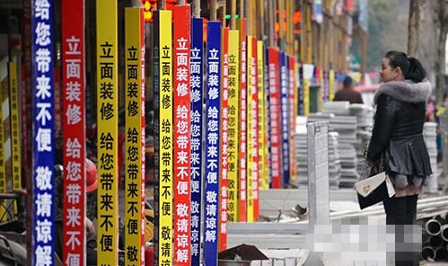 脚手架贴上了五颜六色的标语:"立面装修,给您带来不便,敬请谅解